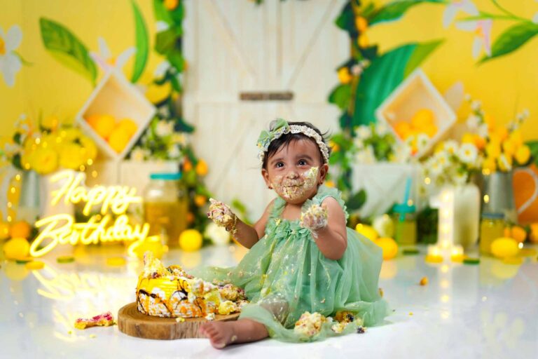 Ein fröhliches Cake-Smash-Shooting zum ersten Geburtstag, mit gelb-grüner Zitronen-Dekoration und lachendem Baby im grünen Kleid.