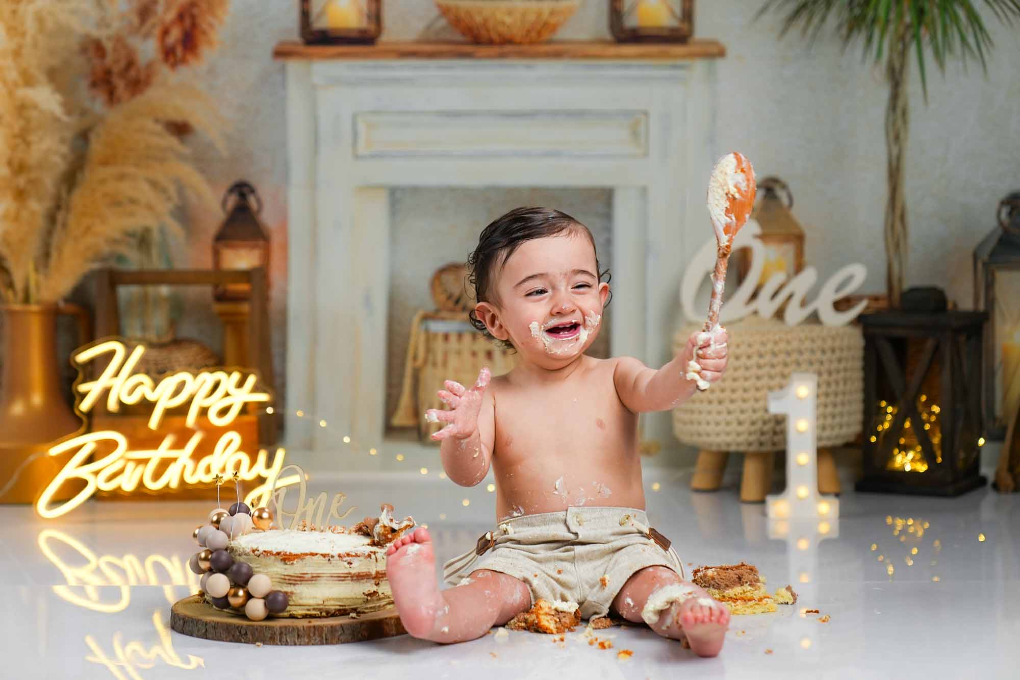 Lachender Junge beim Cake-Smash mit weißem Kuchen und Holzlöffel