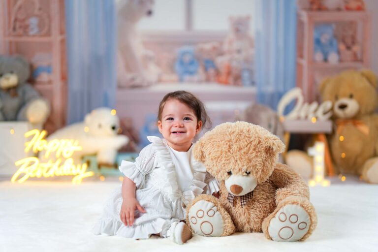 Mädchen im weißen Kleid neben einem großen braunen Teddybären.