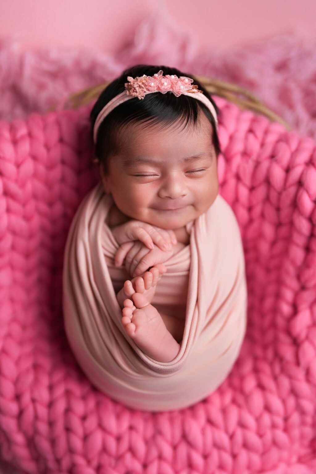 Lächelndes Neugeborenes auf rosa Hintergrund, eingewickelt, Studio Wien