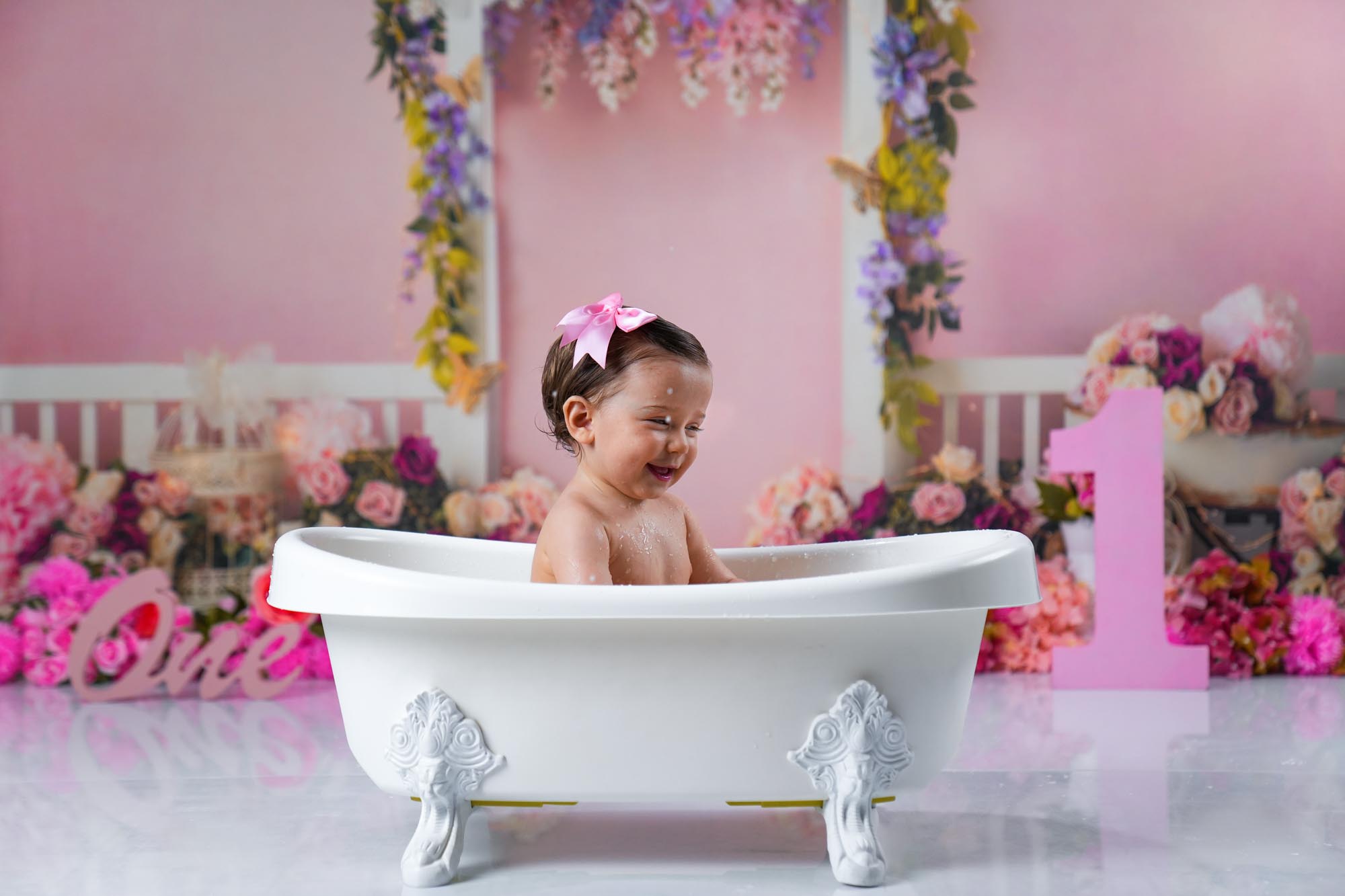Baby im rosa Haarband beim Badeshooting nach dem Cake Smash im Fotostudio Wien