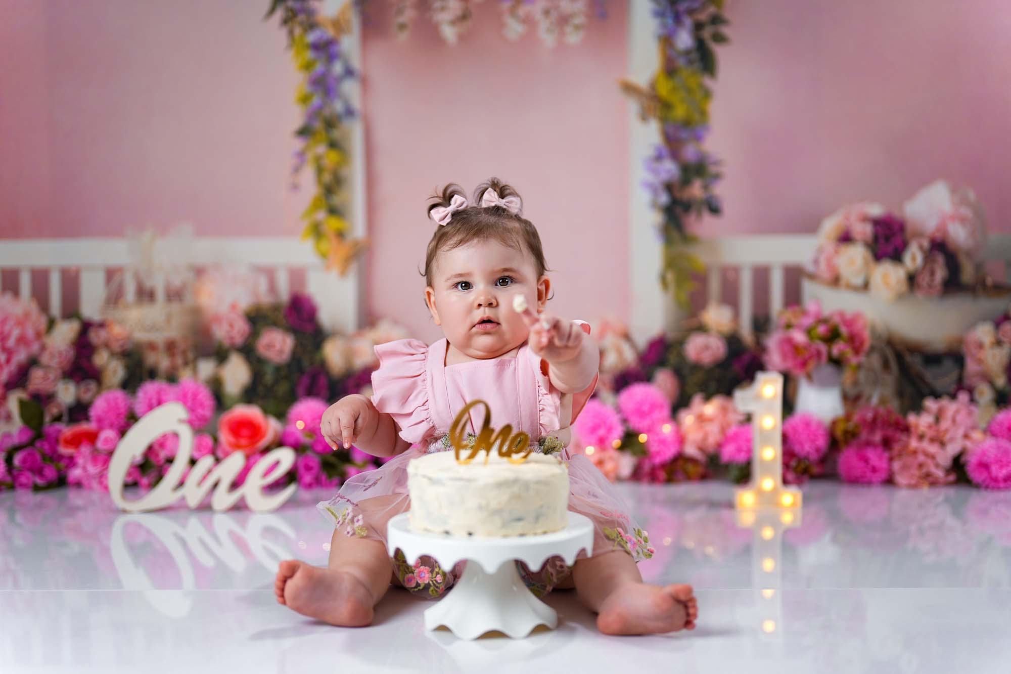 Baby im rosa Kleid mit Geburtstagskuchen beim Cake Smash Shooting in Wien