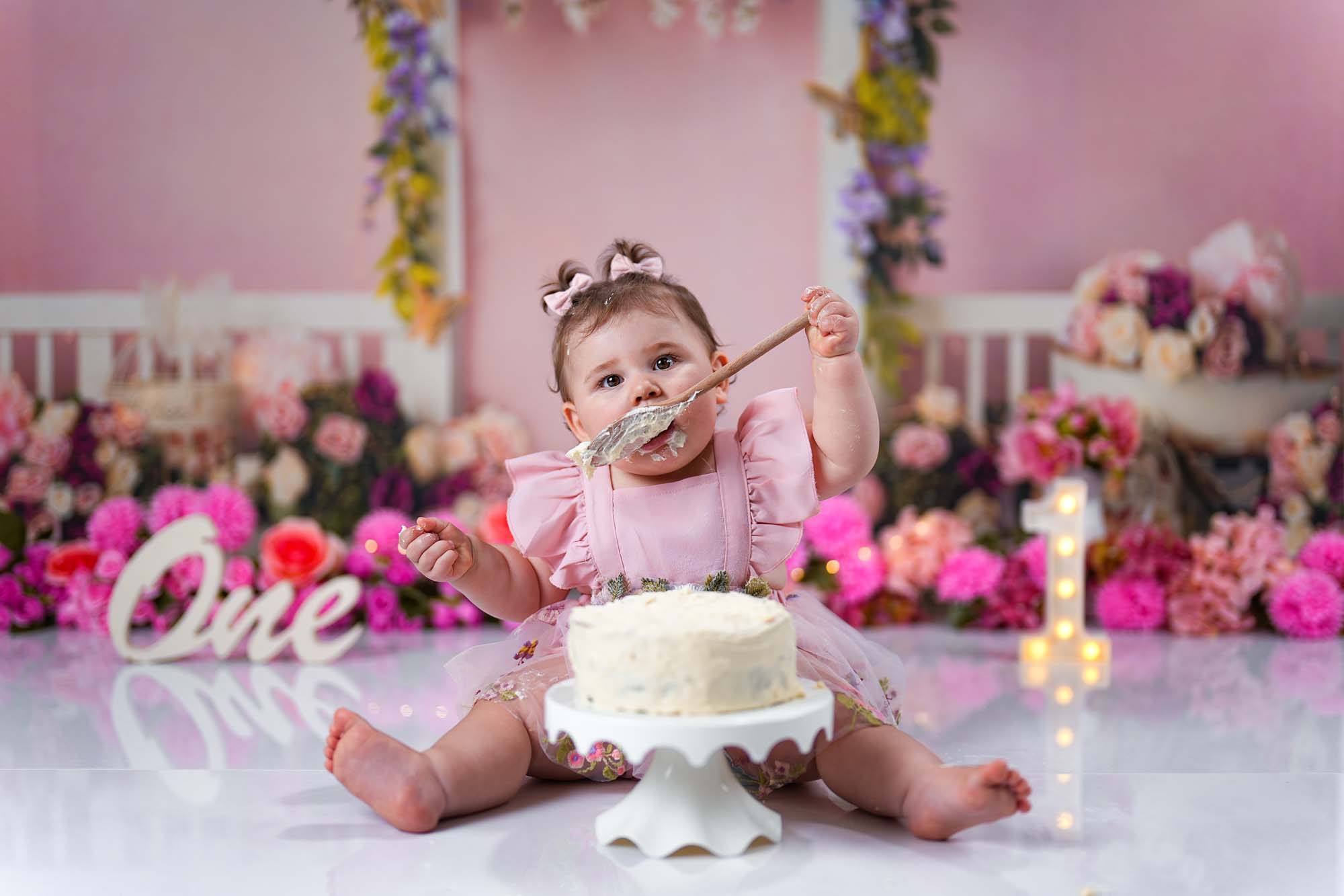 Baby im rosa Kleid mit Schleifen beim Cake Smash Shooting in Wien