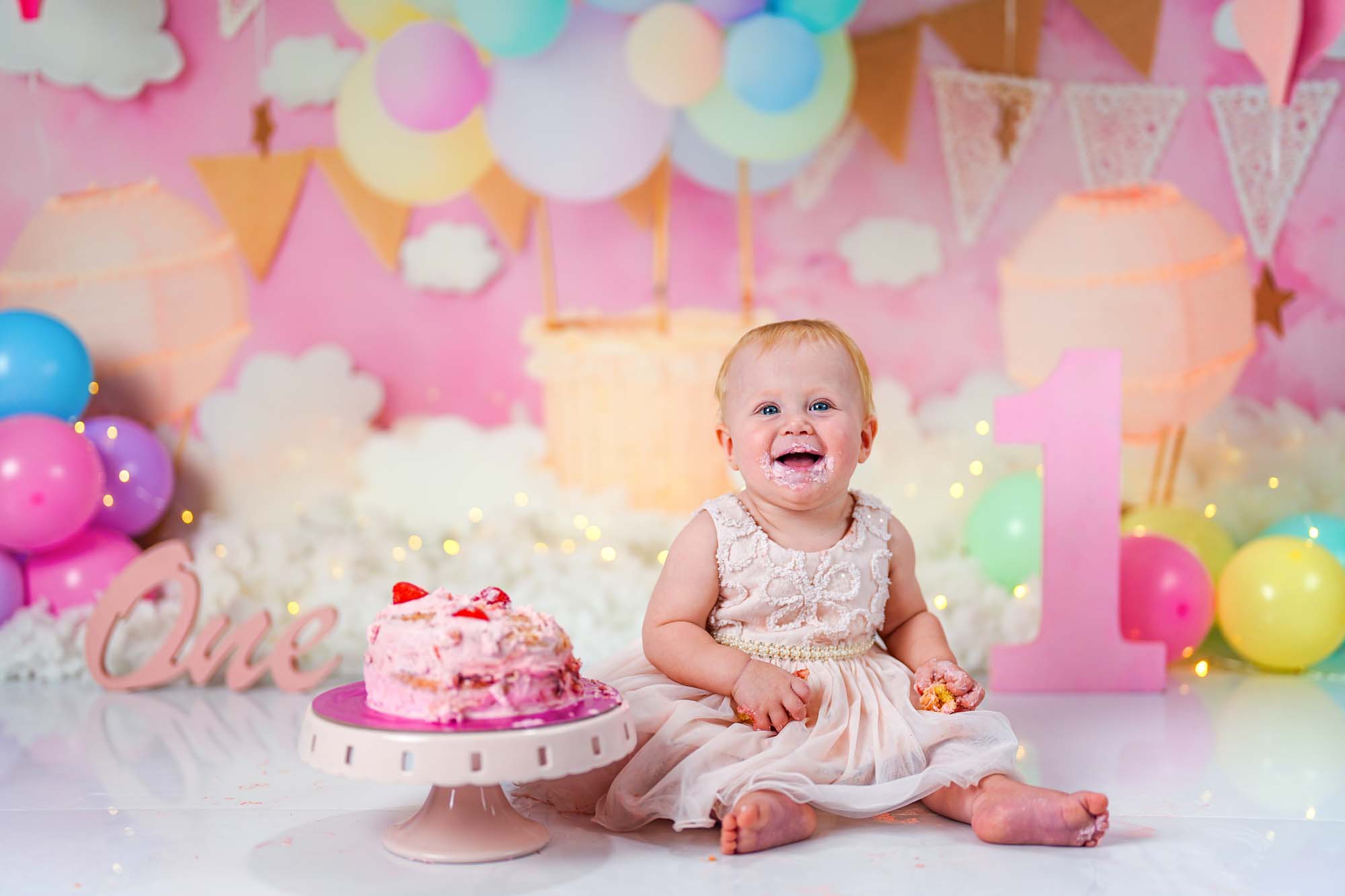 Baby im cremefarbenen Kleid beim Cake Smash Shooting zum 1. Geburtstag in Wien