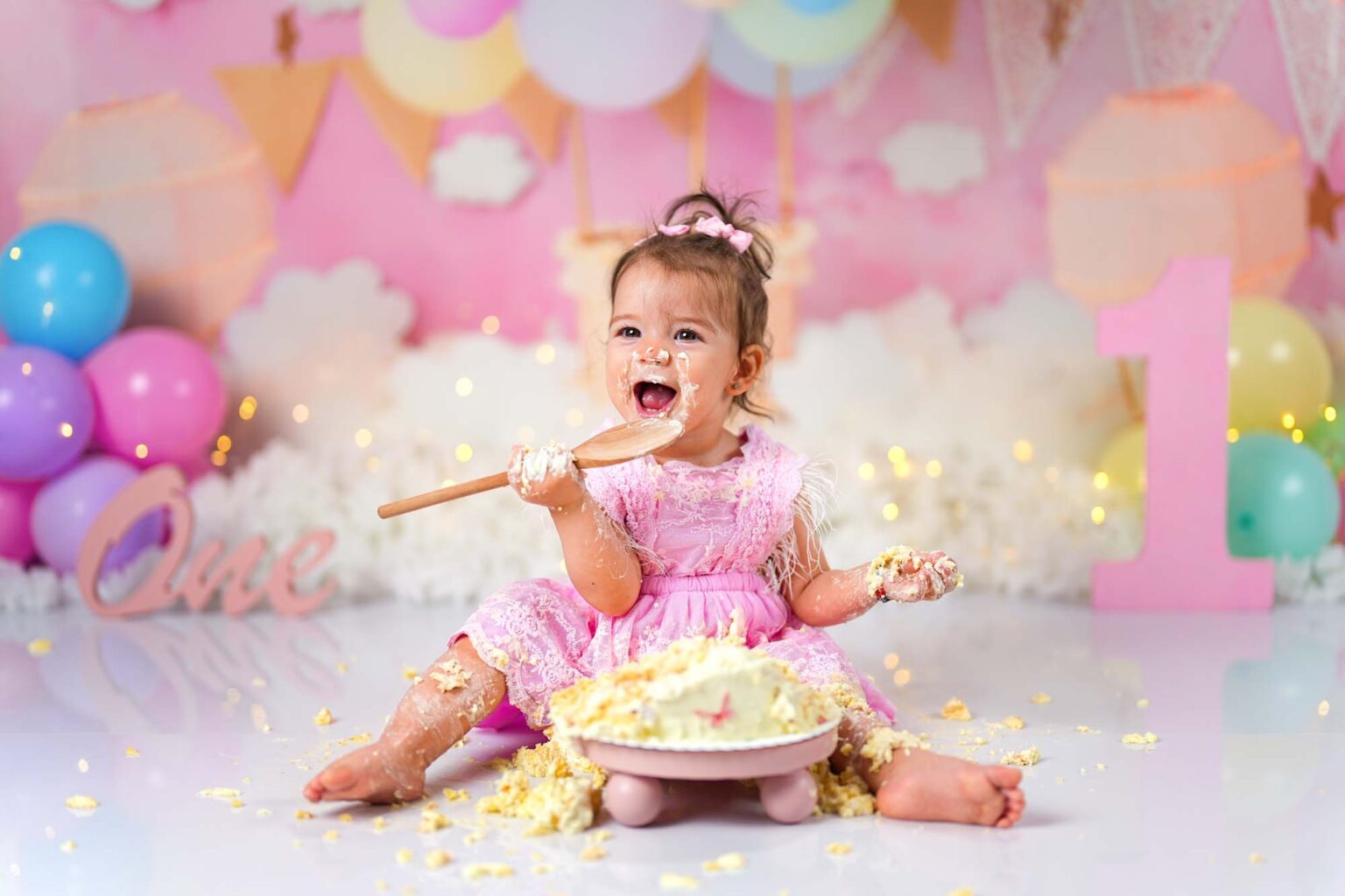 Baby im rosa Spitzenkleid beim fröhlichen Cake Smash Shooting in Wien