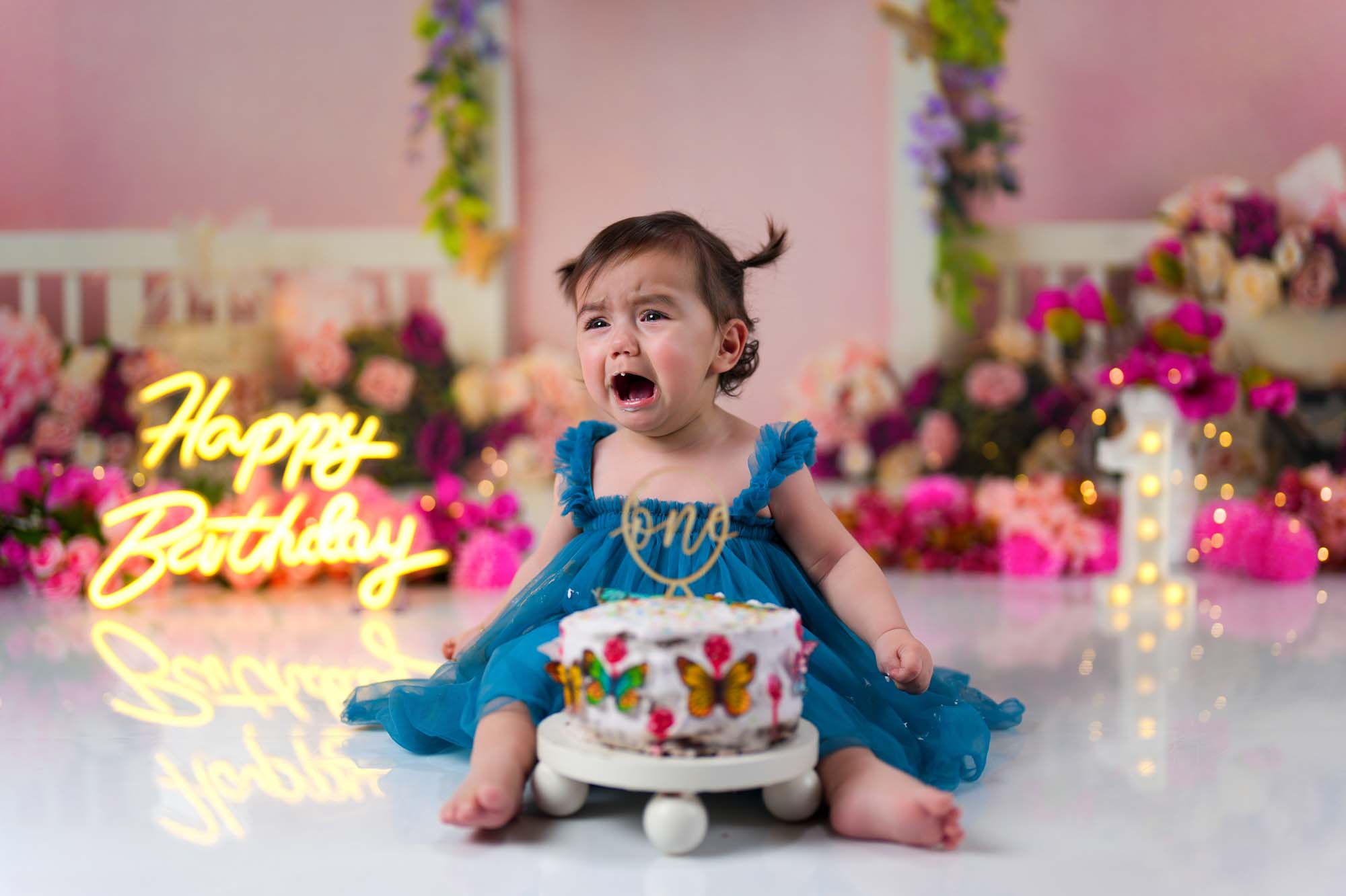 Weinendes einjähriges Mädchen beim Cake Smash Shooting mit Geburtstagskuchen