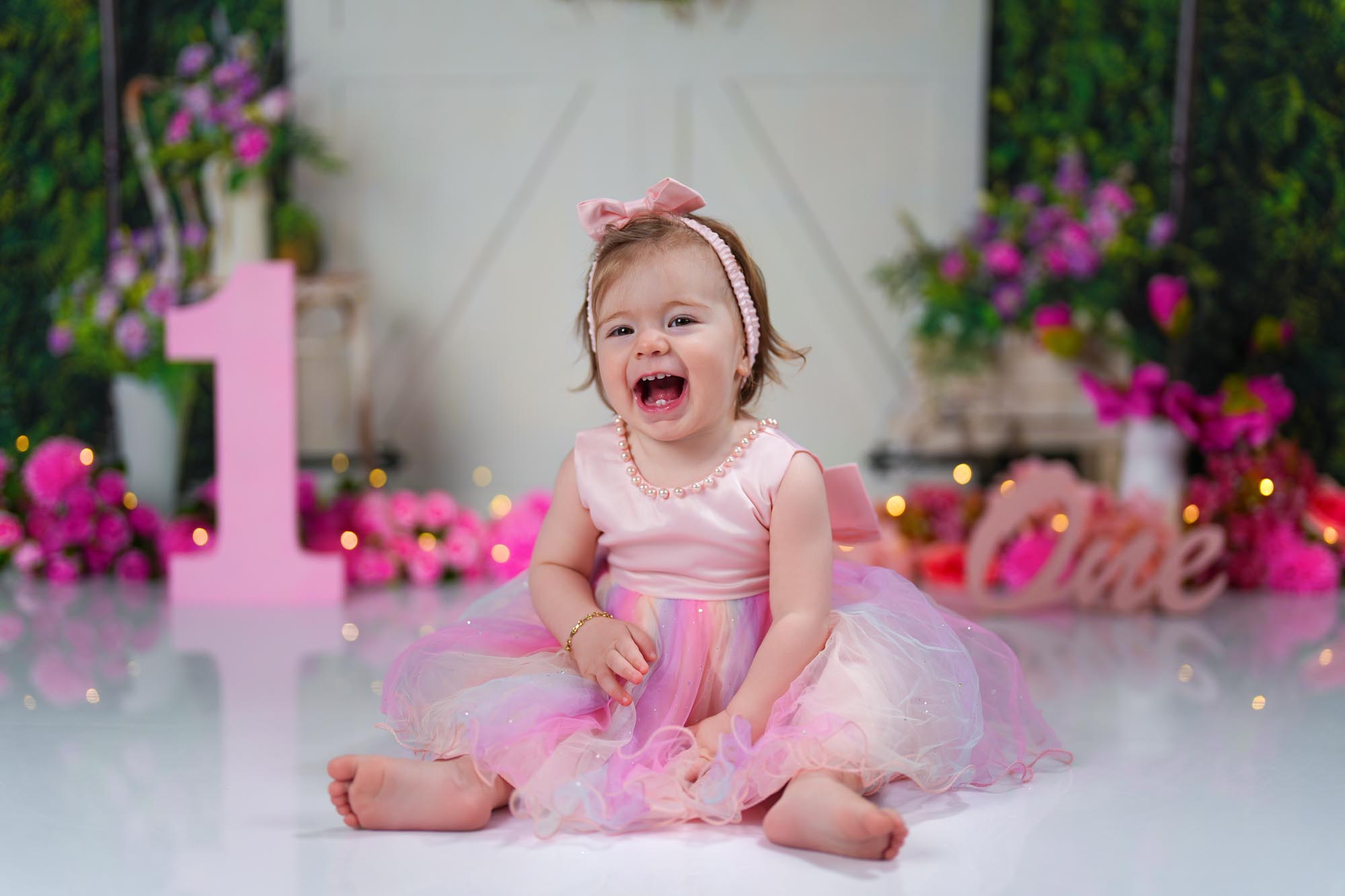 Glückliches einjähriges Mädchen in rosa Kleid bei Cake Smash Shooting im Fotostudio Wien Liesing