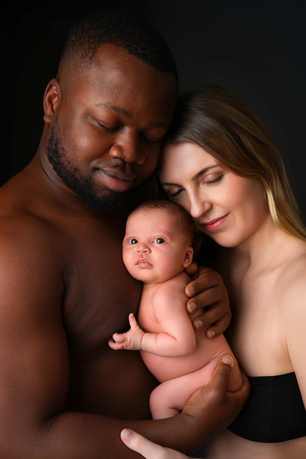 Eltern halten ihr Neugeborenes vor beigem Hintergrund – Fotograwien Wien